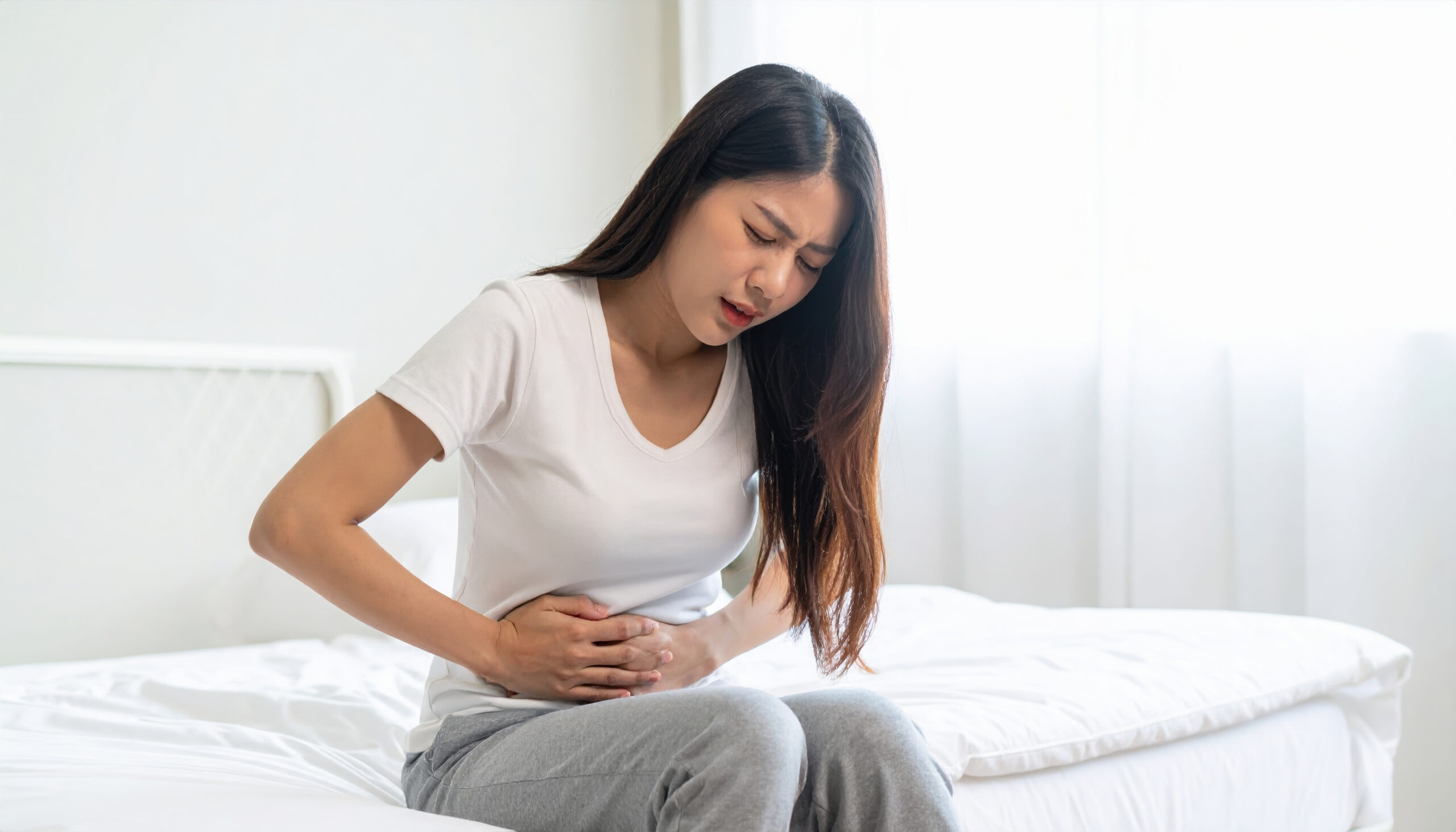 Distressed woman experiencing stomach discomfort and painful bloating after returning home.