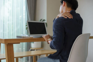 A young man sits at his desk at home using a computer.